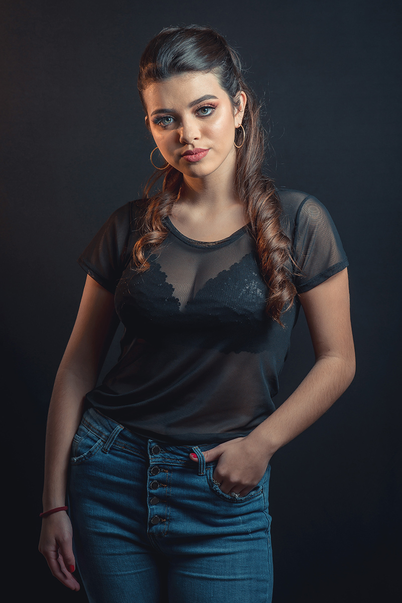Modelo posando em estúdio com fundo preto usando uma blusa preta transparente e calça jeans. Olhos verdes chamando atenção neste lindo editorial de moda em estúdio fotográfico. Foto por Marco Moscarelli Fotógrafo Pelotas.