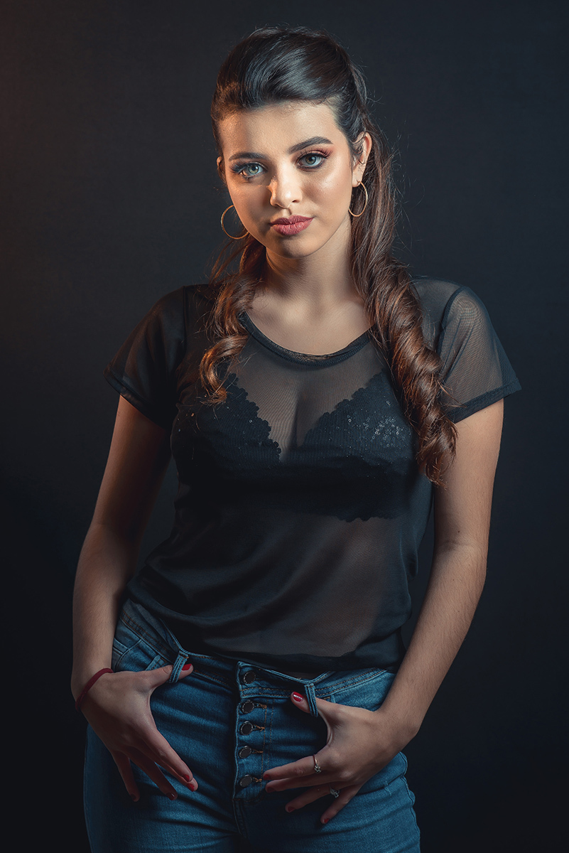 Modelo posando em estúdio com fundo preto usando uma blusa preta transparente e calça jeans. Olhos verdes chamando atenção neste lindo editorial de moda em estúdio fotográfico. Foto por Marco Moscarelli Fotógrafo Pelotas.