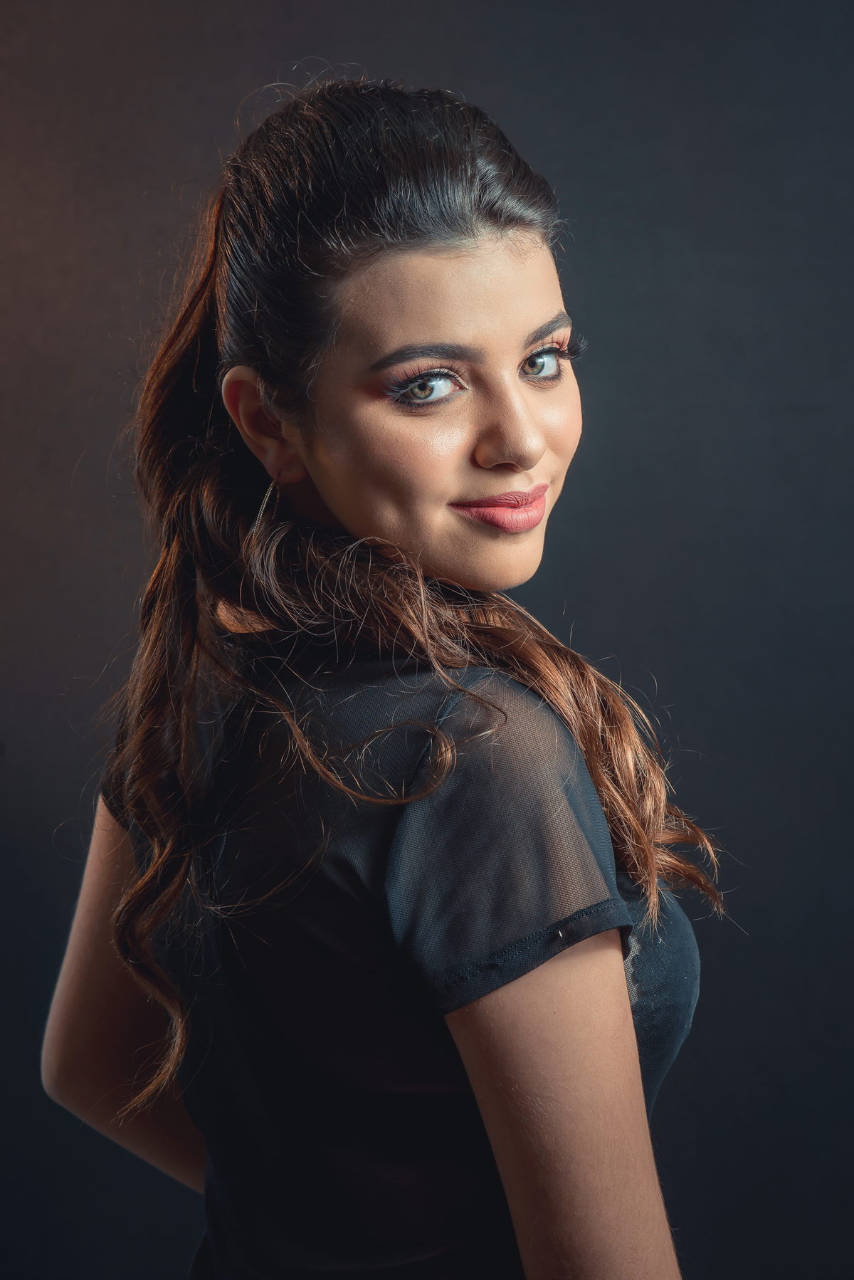 Modelo posando em estúdio com fundo preto usando uma blusa preta transparente e calça jeans. Olhos verdes chamando atenção neste lindo editorial de moda em estúdio fotográfico. Foto por Marco Moscarelli Fotógrafo Pelotas.