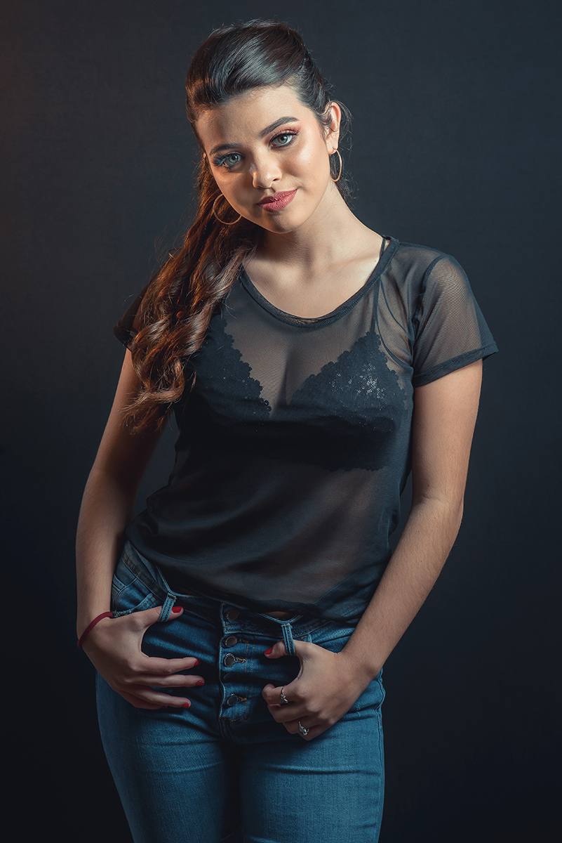 Modelo posando em estúdio com fundo preto usando uma blusa preta transparente e calça jeans. Olhos verdes chamando atenção neste lindo editorial de moda em estúdio fotográfico. Foto por Marco Moscarelli Fotógrafo Pelotas.