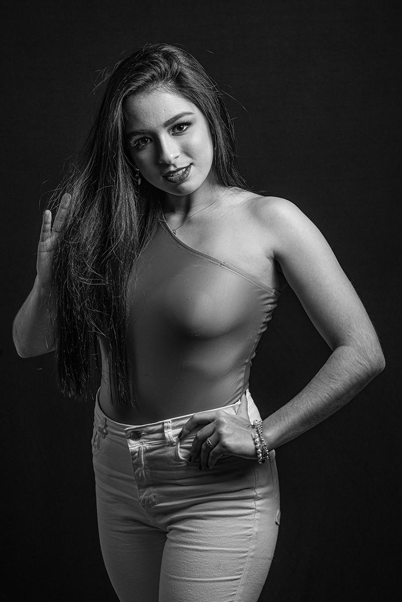 Modelo posando em estúdio com fundo preto usando uma blusa rosa e calça jeans branca. Olhos verdes chamando atenção neste lindo editorial de moda em estúdio fotográfico. Foto por Marco Moscarelli Fotógrafo Pelotas. 