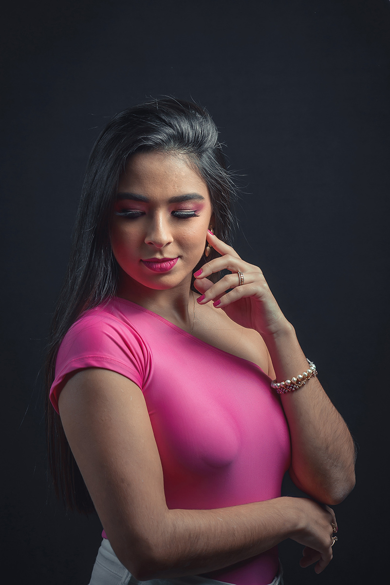 Modelo posando em estúdio com fundo preto usando uma blusa rosa e calça jeans branca. Olhos verdes chamando atenção neste lindo editorial de moda em estúdio fotográfico. Foto por Marco Moscarelli Fotógrafo Pelotas. 