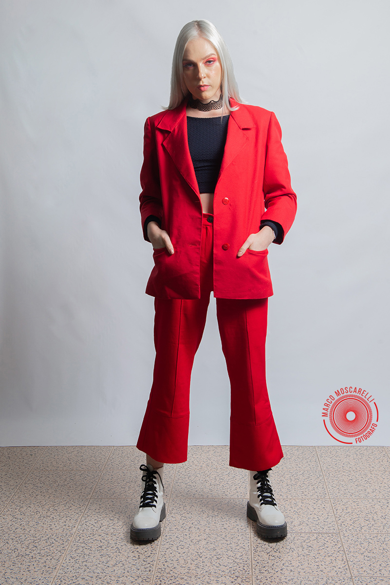Modelo posando em fundo Branco usando um terno vermelho em editorial de moda em estúdio fotográfico. Foto por Marco Moscarelli Fotógrafo Pelotas.