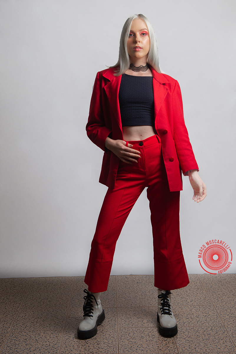 Modelo posando em fundo Branco usando um terno vermelho em editorial de moda em estúdio fotográfico. Foto por Marco Moscarelli Fotógrafo Pelotas.