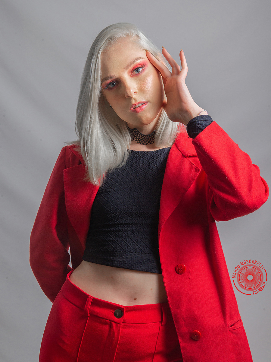 Modelo posando em fundo Branco usando um terno vermelho em editorial de moda em estúdio fotográfico. Foto por Marco Moscarelli Fotógrafo Pelotas.