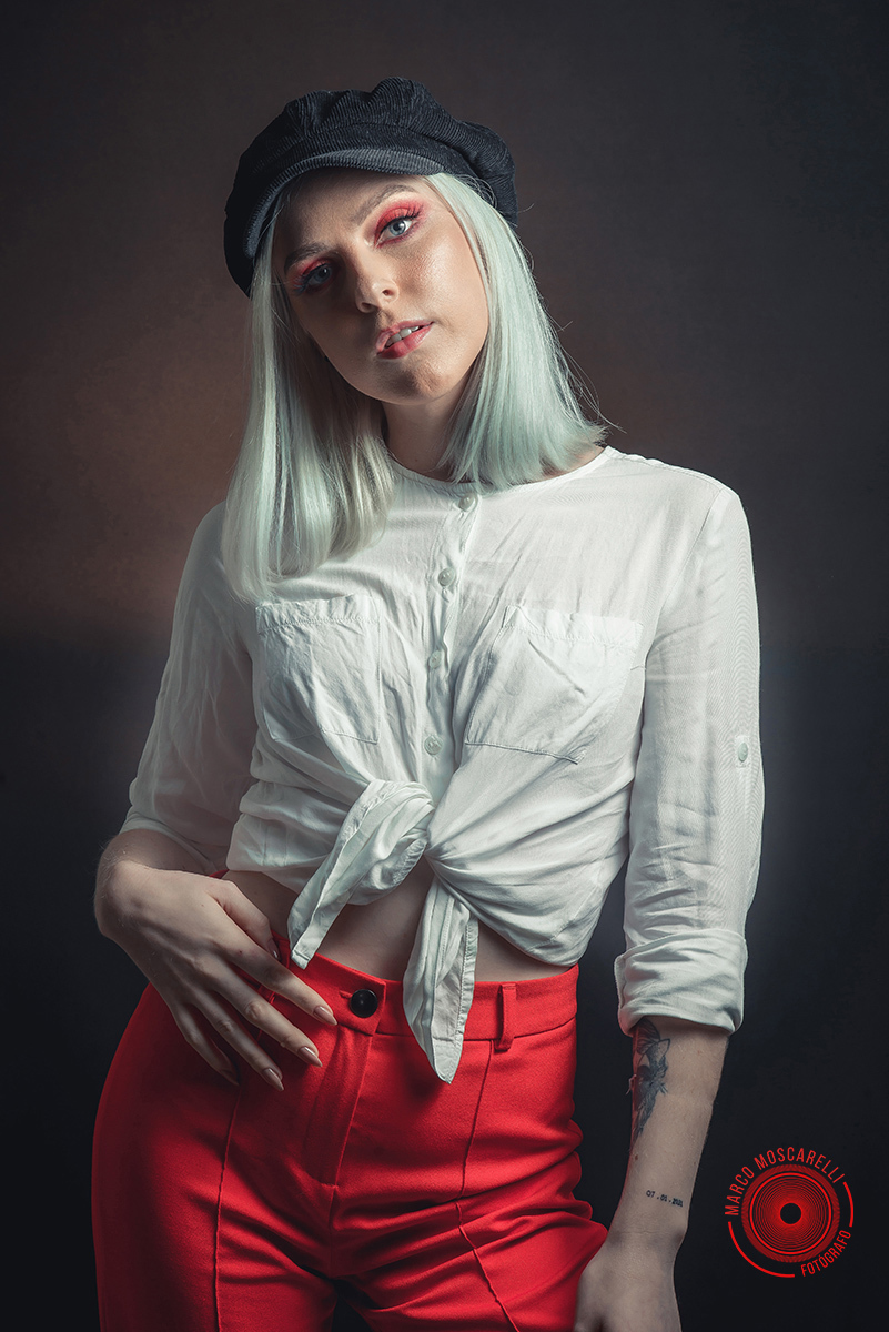 Modelo posando em fundo Preto usando uma calça vermelha e blusinha branca em editorial de moda em estúdio fotográfico. Foto por Marco Moscarelli Fotógrafo Pelotas.