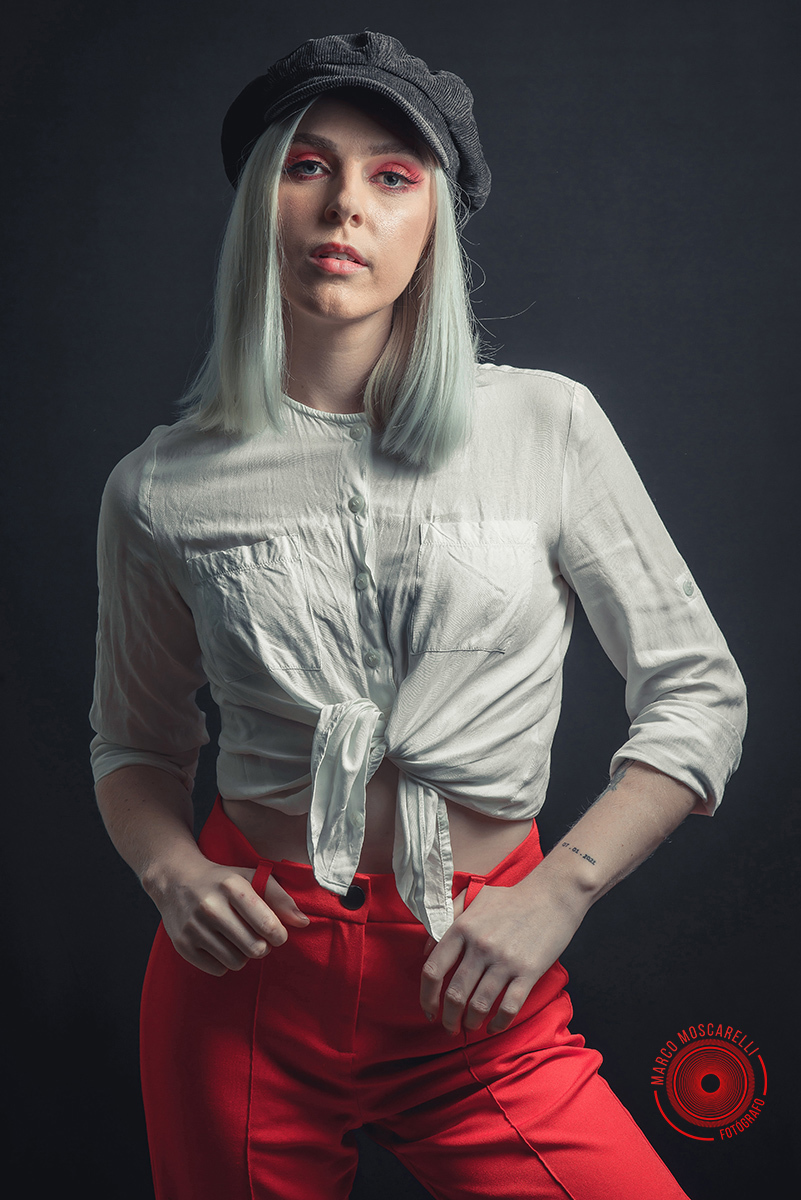 Modelo posando em fundo Preto usando uma calça vermelha e blusinha branca em editorial de moda em estúdio fotográfico. Foto por Marco 