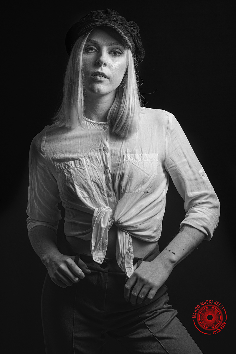 Modelo posando em fundo Preto usando uma calça vermelha e blusinha branca em editorial de moda em estúdio fotográfico. Foto por Marco 