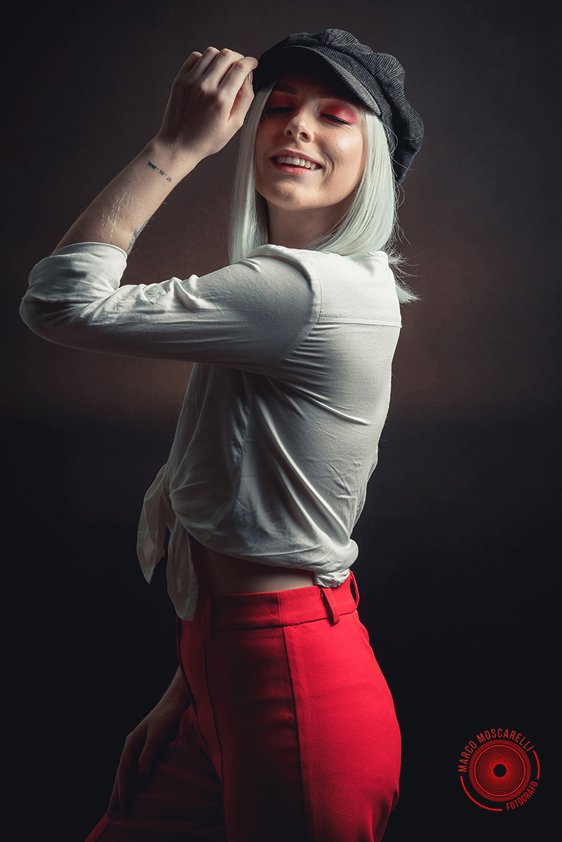 Modelo posando em fundo Preto usando uma calça vermelha e blusinha branca em editorial de moda em estúdio fotográfico. Foto por Marco 