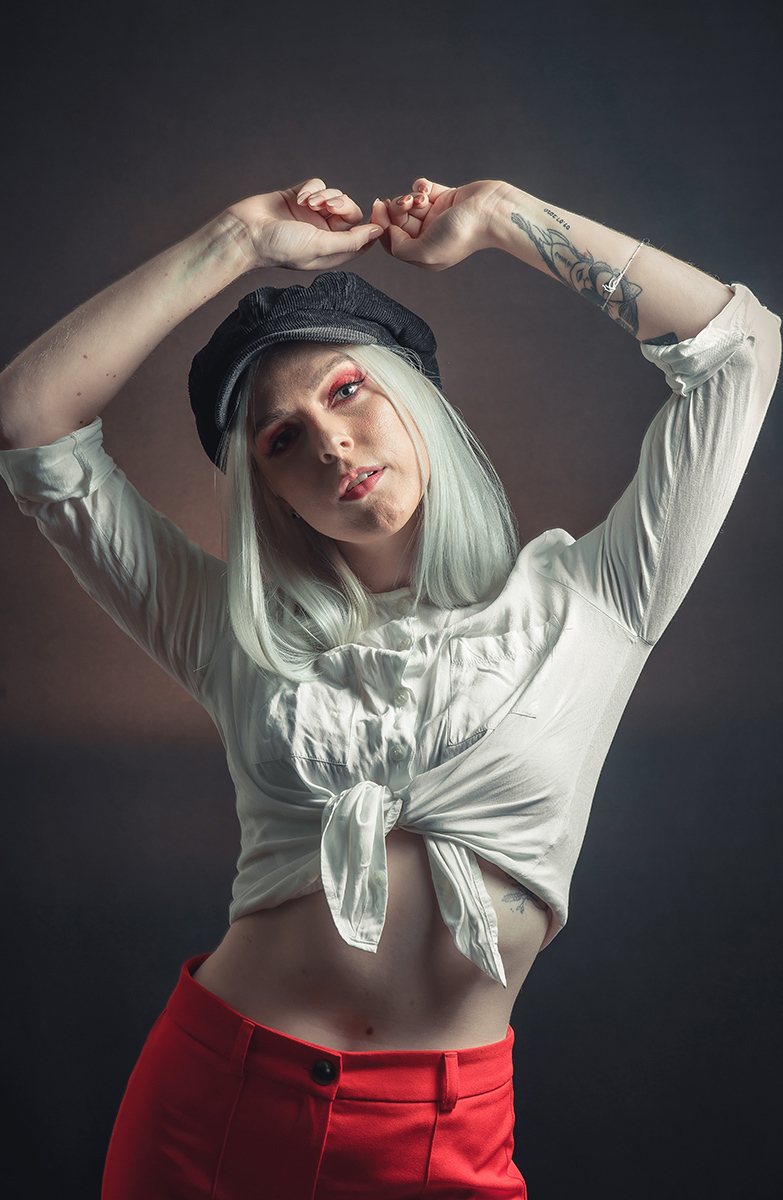 Modelo posando em fundo Preto usando uma calça vermelha e blusinha branca em editorial de moda em estúdio fotográfico. Foto por Marco 