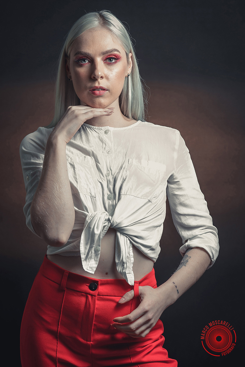 Modelo posando em fundo Preto usando uma calça vermelha e blusinha branca em editorial de moda em estúdio fotográfico. Foto por Marco 
