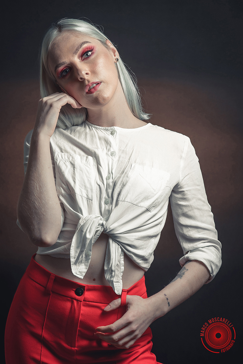 Modelo posando em fundo Preto usando uma calça vermelha e blusinha branca em editorial de moda em estúdio fotográfico. Foto por Marco 