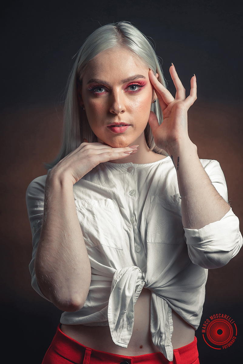 Modelo posando em fundo Preto usando uma calça vermelha e blusinha branca em editorial de moda em estúdio fotográfico. Foto por Marco 