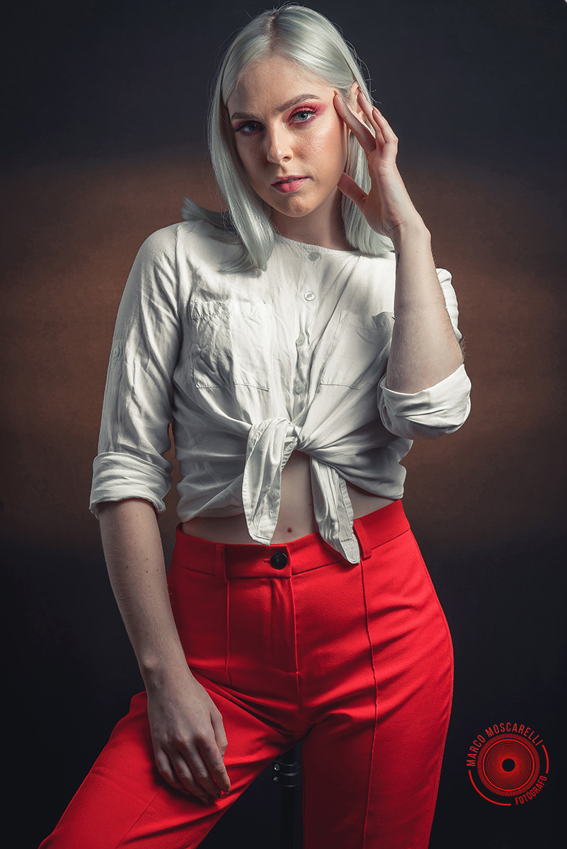 Modelo posando em fundo Preto usando uma calça vermelha e blusinha branca em editorial de moda em estúdio fotográfico. Foto por Marco 