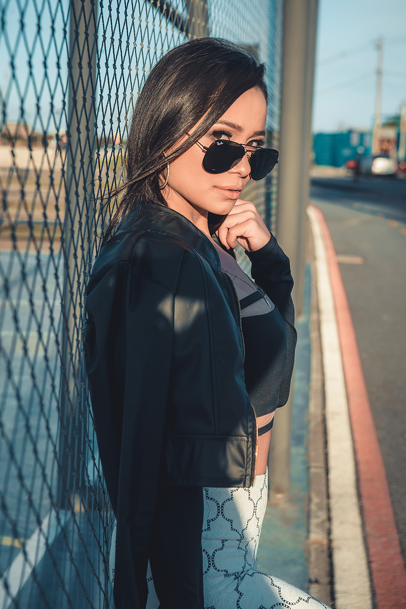 Modelo posando  encostada em tela de quadra de esportes, usando roupas despojadas  em ensaio fotográfico realizado no parque Una em Pelotas. Foto por Marco Moscarelli Fotógrafo Pelotas.