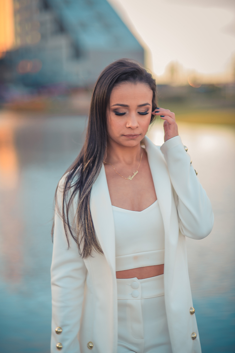 Modelo posando com a mão no rosto e usando um terninho branco para fotografia em ensaio fotográfico realizado no parque Una em Pelotas. Foto por Marco Moscarelli Fotógrafo Pelotas.