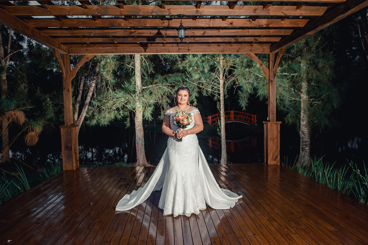 Ensaio dos noivos após a cerimônia de casamento, noiva posando para fotografia embaixo de estrutura de madeira. Foto por Marco Moscarelli Fotógrafo Pelotas.