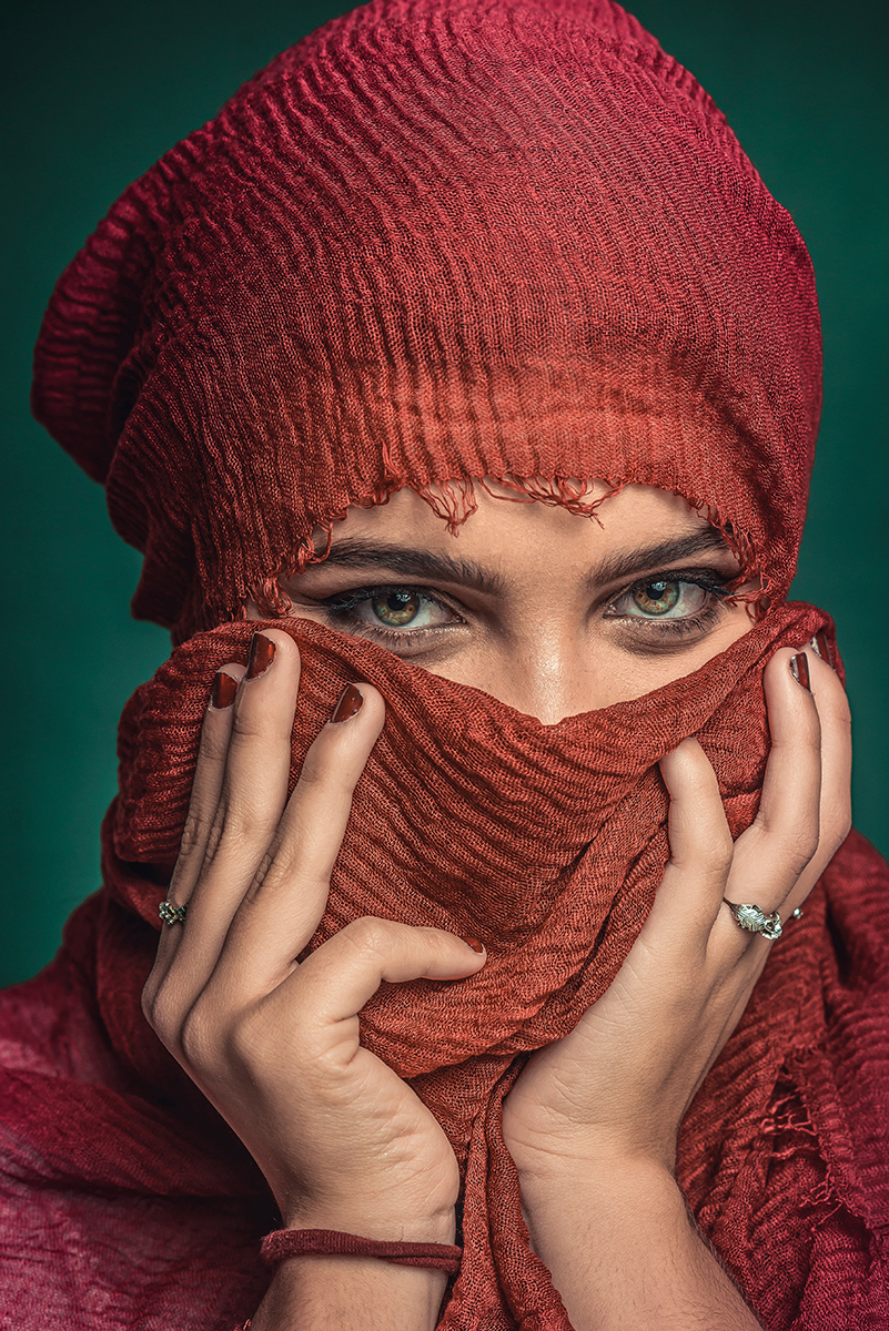 Linda reprodução de fotografia de Steve McCurry. Modelo usando lenço vermelho no rosto com fundo verde. Foto por Marco Moscarelli Fotógrafo Pelotas.