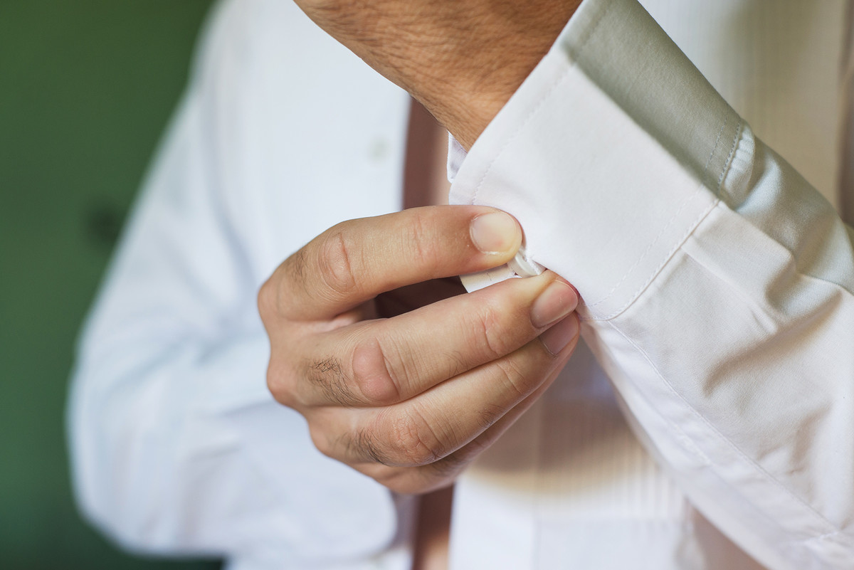 Detalhe do noivo abotoando a manga da camisa  para o casamento