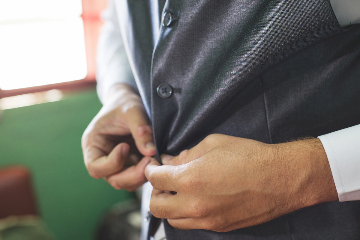 Detalhe do noivo abotoando a manga da camisa  para o casamento
