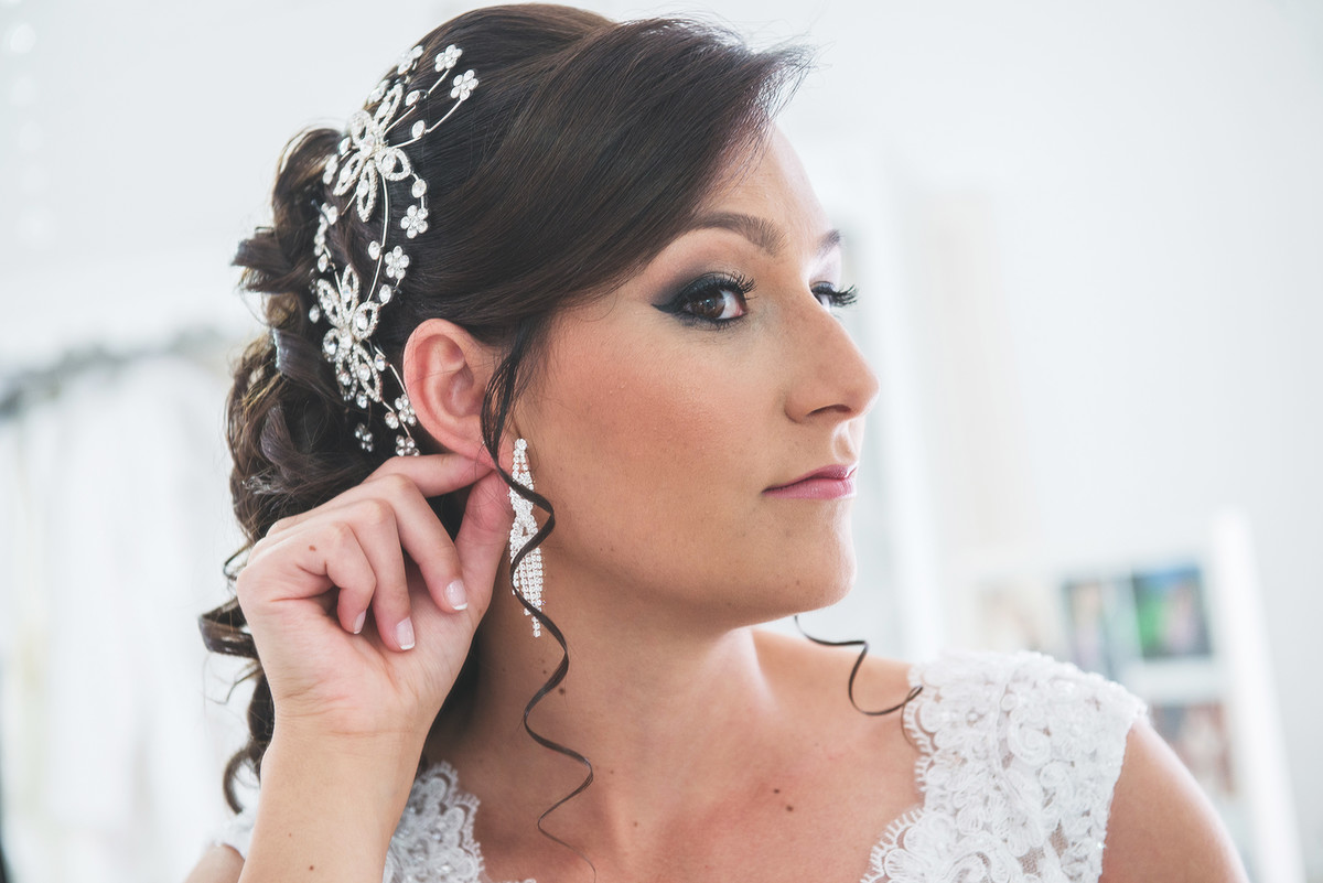 Noiva conferindo os últimos detalhes antes do casamento, olhando o brinco no espelho.