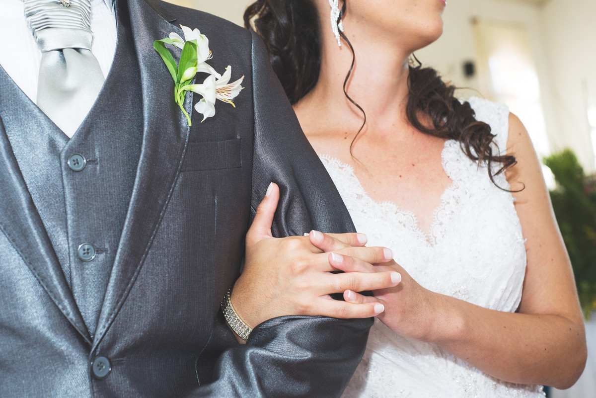 detalhe da noiva abbraçando o braço do noivo, detalhe das mãos.