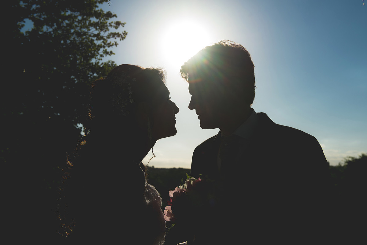Foto contra a luz do casal de noivos.