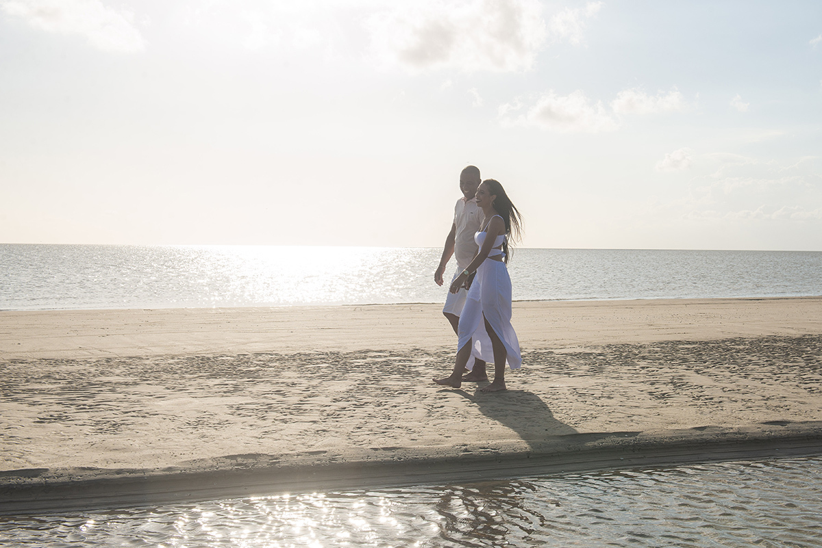 Casal caminhando de mãos dadas pela praia durante seu ensaio pré wedding na praia da capilha. Foto por Marco Moscarelli Fotógrafo Pelotas.