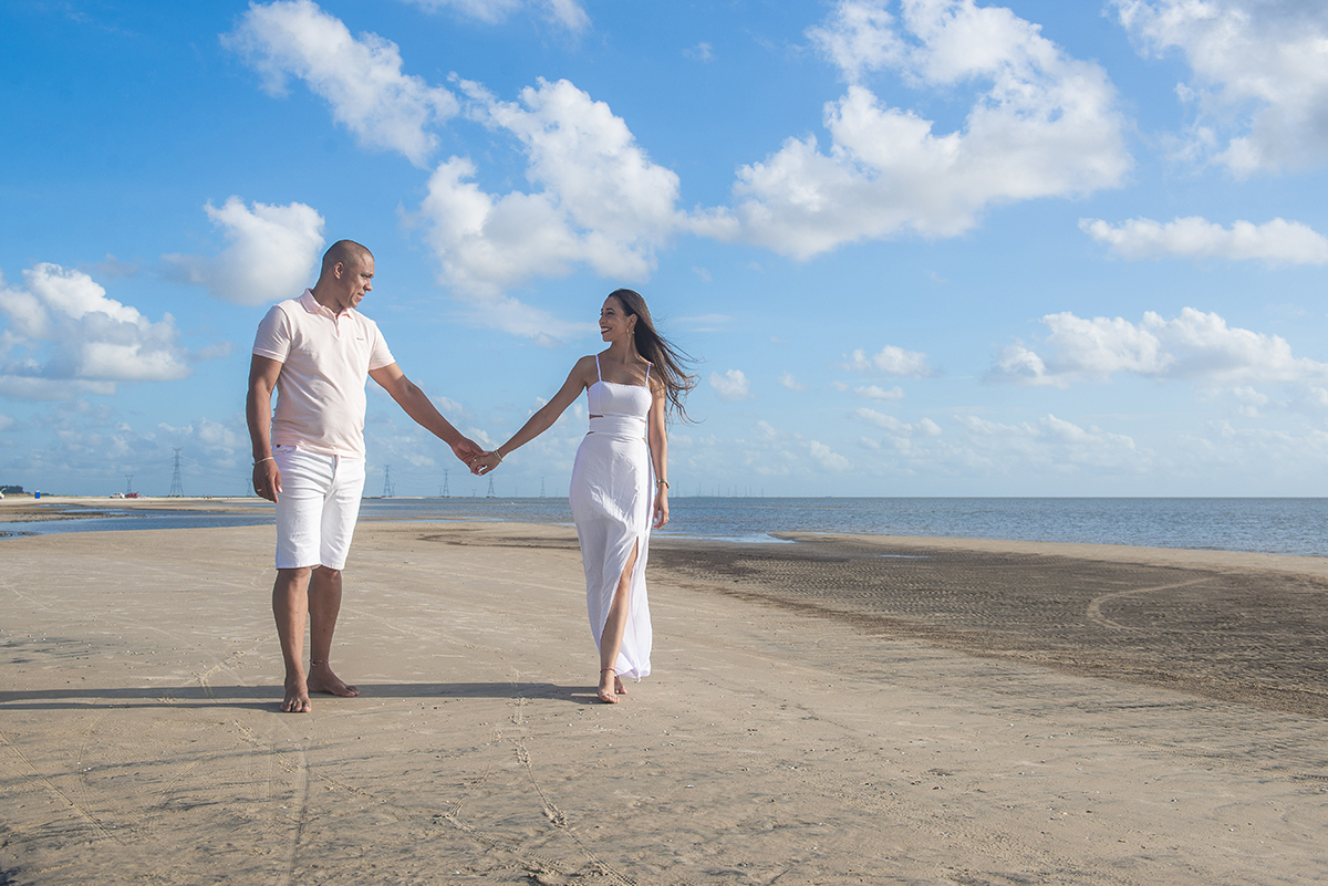 Casal caminhando de mãos dadas pela praia durante seu ensaio pré wedding na praia da capilha. Foto por Marco Moscarelli Fotógrafo Pelotas.