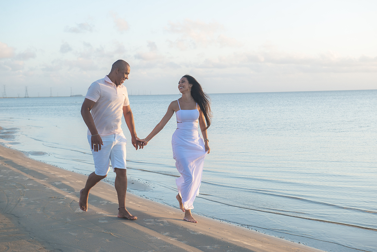 Casal caminhando de mãos dadas pela praia durante seu ensaio pré wedding na praia da capilha. Foto por Marco Moscarelli Fotógrafo Pelotas.