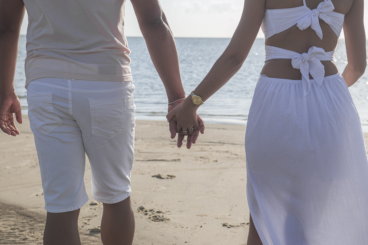 Casal caminhando de mãos dadas pela praia durante seu ensaio pré wedding na praia da capilha. Foto por Marco Moscarelli Fotógrafo Pelotas.