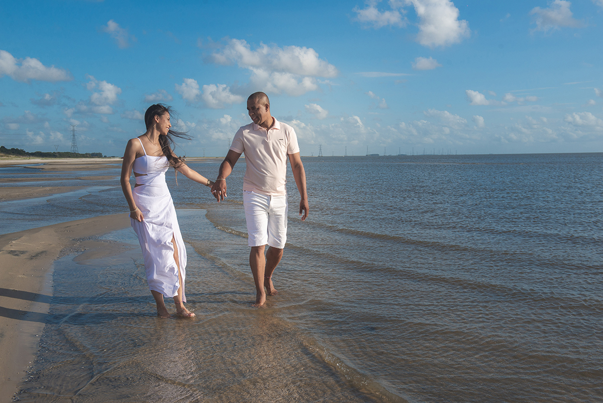 Casal caminhando de mãos dadas pela praia durante seu ensaio pré wedding na praia da capilha. Foto por Marco Moscarelli Fotógrafo Pelotas.