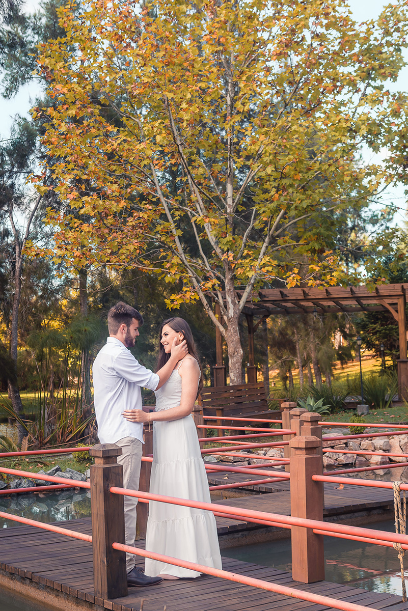 Fotografia dos noivos trocando carinhos em uma passarela de jardim japonês durante seu ensaio pré wedding no seu pré casamento na chácara Fiss. Foto por Marco Moscarelli Fotógrafo Pelotas.