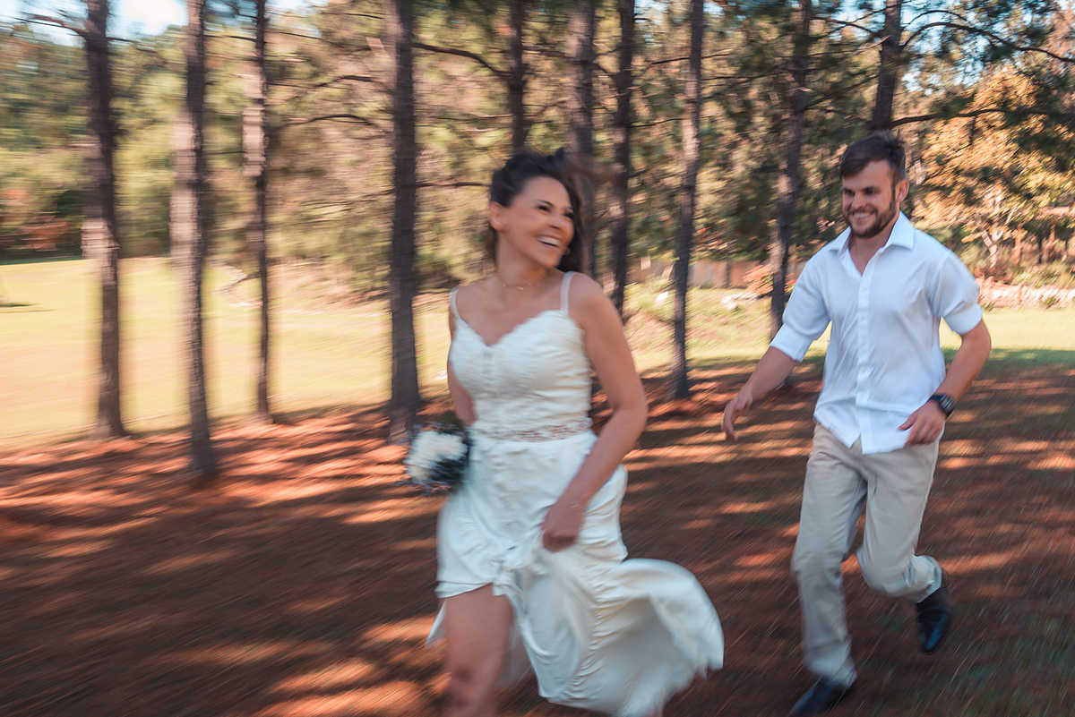 Casal de noivos posando para foto levemente desfocada correndo em um lindo gramado em meio a natureza durante seu ensaio pré wedding no seu pré casamento na chácara Fiss. Foto por Marco Moscarelli Fotógrafo Pelotas.