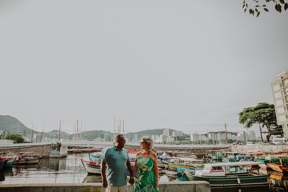 Casal caminhando de mãos dadas na Mureta da Urca, Rio de Janeiro, durante ensaio comemorativo de casamento.