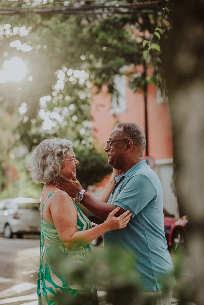 Casal maduro sorrindo enquanto segura o rosto um do outro durante ensaio fotográfico no Rio de Janeiro.