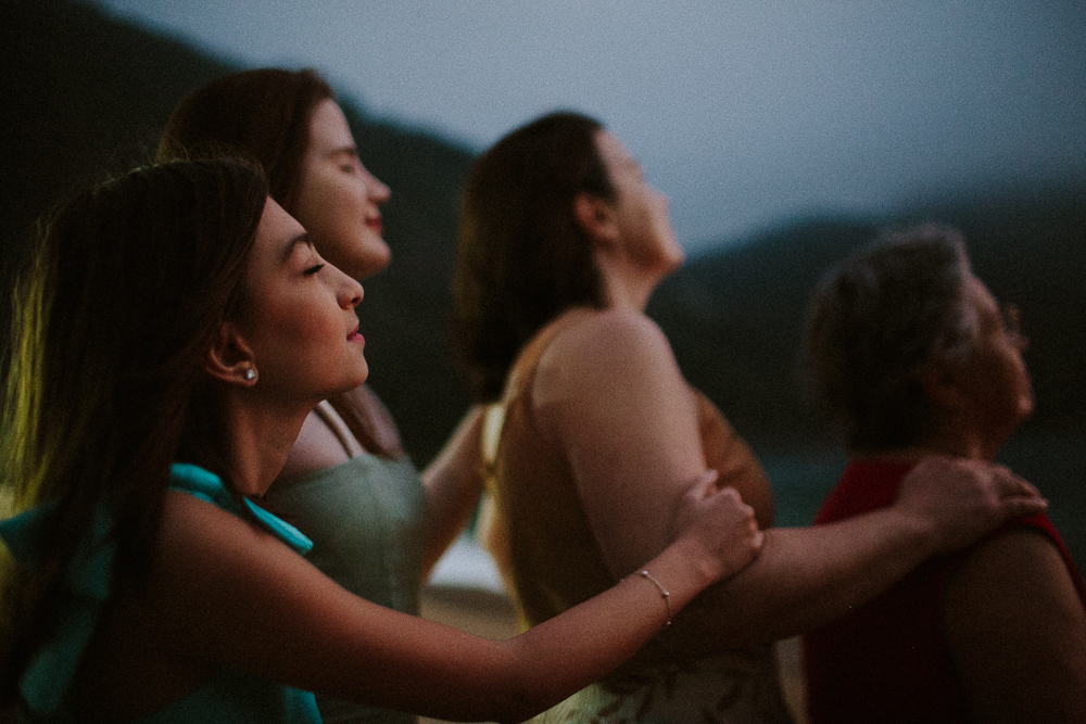Família com três gerações reunidas durante ensaio fotográfico na Praia Vermelha, Rio de Janeiro em um retrato poetico e cinematografico.