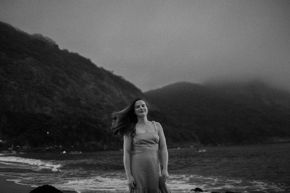 Retrato em preto e branco de jovem mulher da família na Praia Vermelha no nascer do sol em dia nublado.