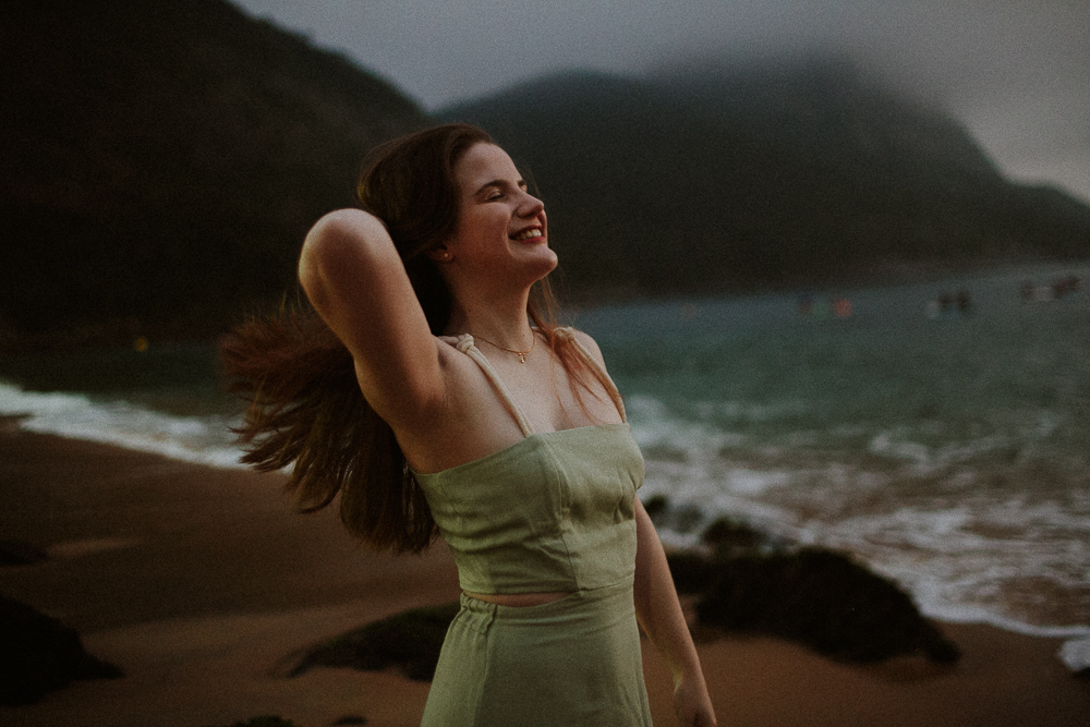 Mulher sorrindo durante ensaio fotográfico de família no Rio de Janeiro na Praia Vermelha como um quadro de Leonardo Da Vinci.