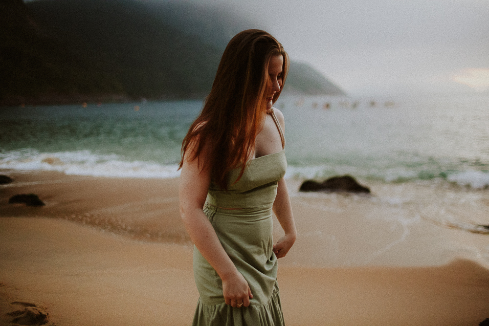 Mulher caminhando pela areia na Praia Vermelha durante ensaio de família.