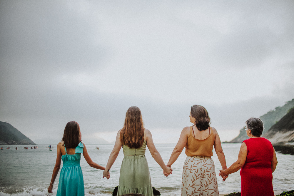 Família de mãos dadas durante ensaio fotográfico na Praia Vermelha.