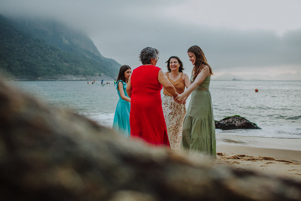 Família reunida caminhando pela areia durante ensaio fotográfico.