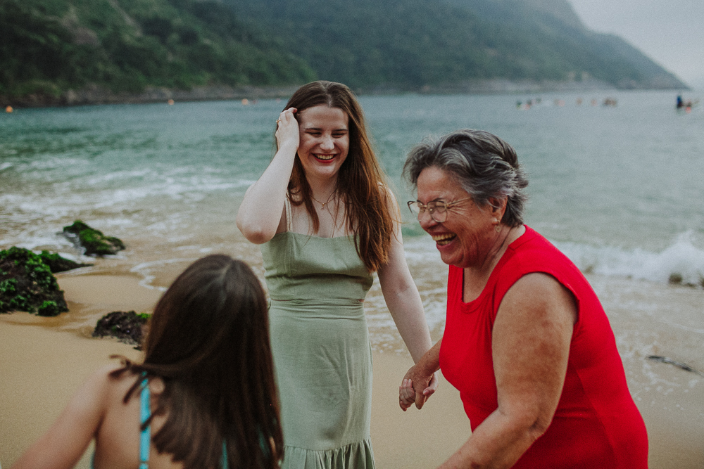 Família brincando na praia durante ensaio fotográfico.