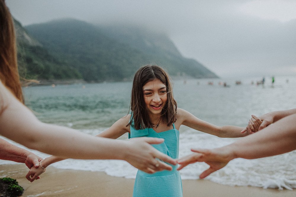Menina brincando de mãos dadas com a família na Praia Vermelha.