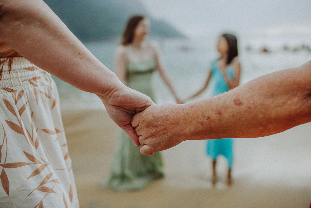 Mãe e avó de mãos dadas durante ensaio de família na Praia Vermelha.