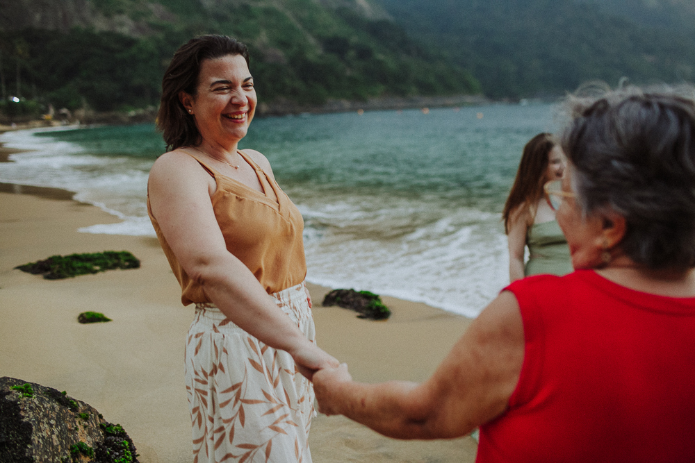 Mãe e avó sorrindo de mãos dadas na Praia Vermelha.