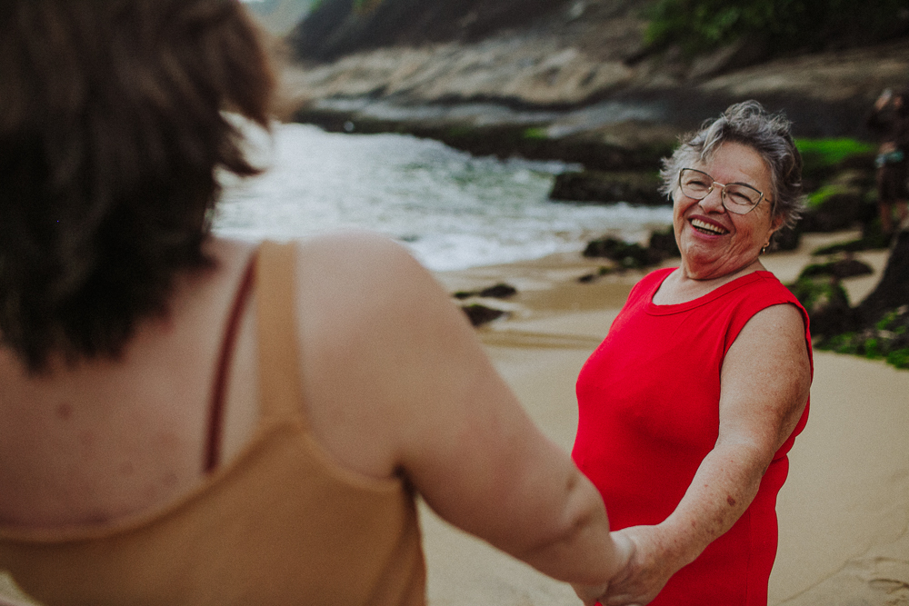 Avó sorrindo enquanto caminha na areia.