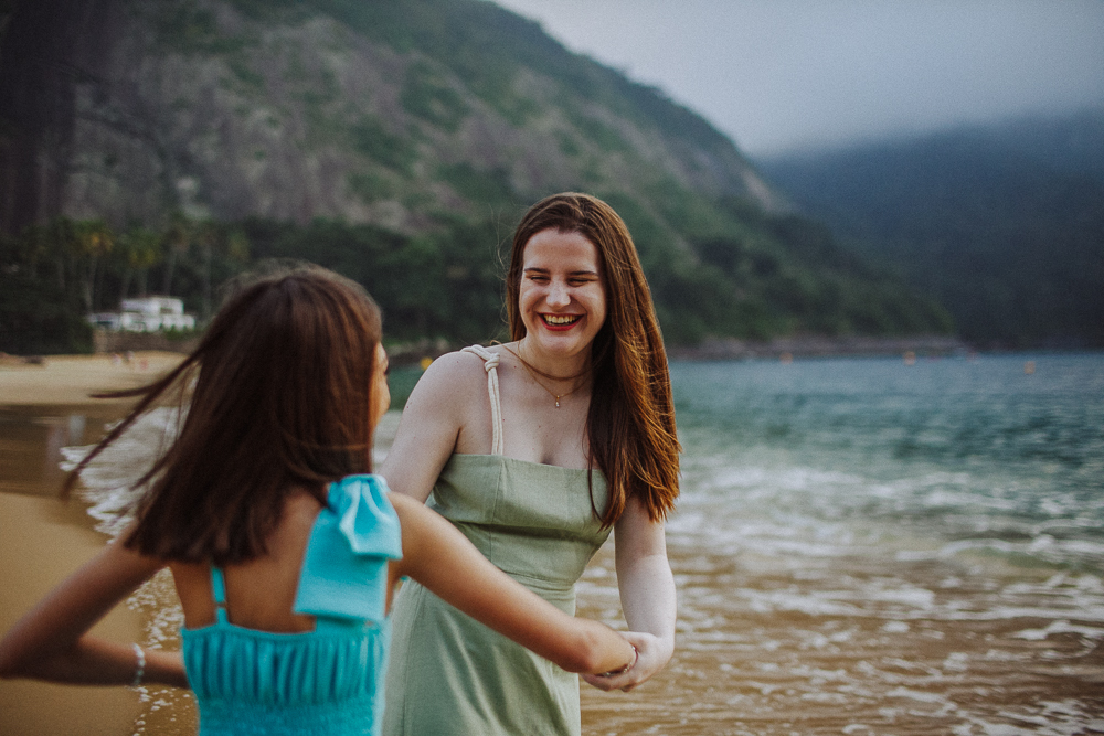 Irmãs brincando de roda na areia da Praia Vermelha.
