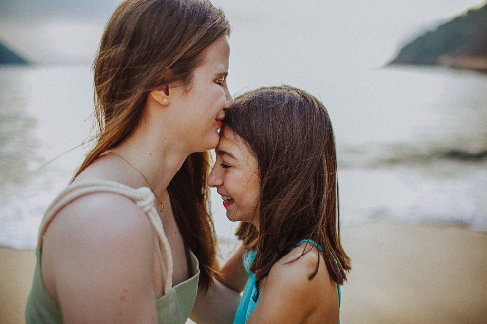 Irmã beijando a testa da irmã durante ensaio de família.