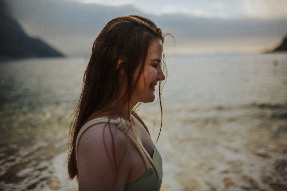 Retrato espontâneo de mulher de perfil sorrindo na praia.